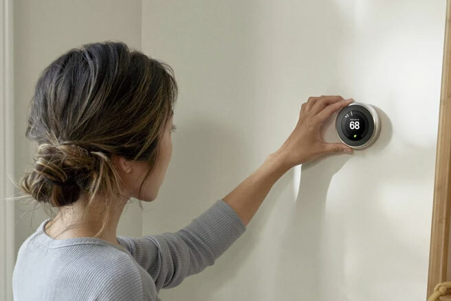 Foto de una mujer ajustando un termostato Nest.