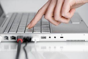 Hand mit Laptop-Computer mit USB-Kabeln