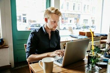 איש צעיר עובד על מחשב נייד בבית קפה