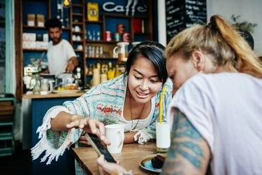 Dua Teman Melihat Gambar Di Smartphone Di Kafe Bersama