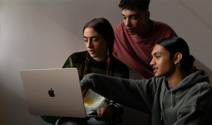 Drie mensen zitten voor een 15-inch MacBook Air, gezien vanaf de achterkant.