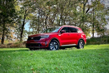 Voorkant bestuurderskant vanuit een hoek van de Kia Sorento Hybrid uit 2021 in een grasveld.