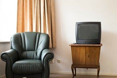 Televisión vintage en armario antiguo de madera, diseño antiguo en el salón con silla vieja