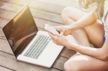 Pige bruger en bærbar computer og smartphone