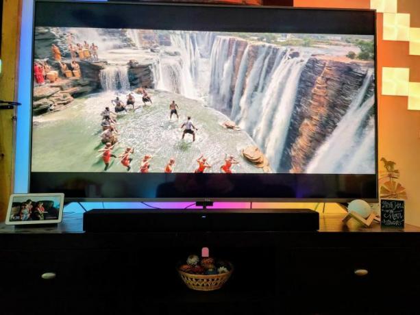 TCL Roku TV Alto R1 Soundbar unter einem Fernseher auf einem Medienständer. 