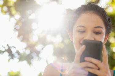 Femeie brunetă fericită trimite mesaje cu smartphone-ul ei