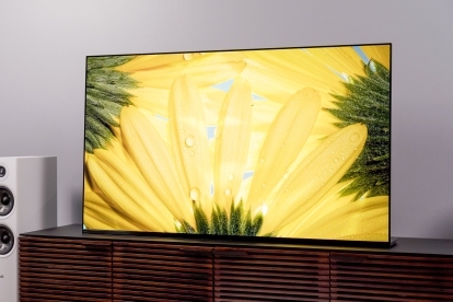 Sony A95K QD-OLED TV står i flukt på mediestativ i tre med fargerike gule blomster på skjermen