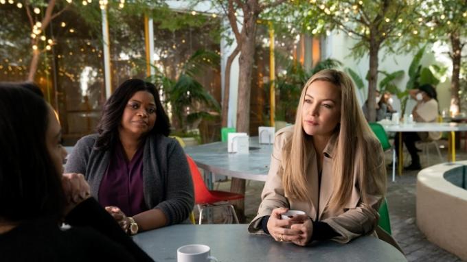 Kate Hudson y Octavia Spencer hablando con alguien en una mesa en una escena de la temporada 2 de Truth Be Told.