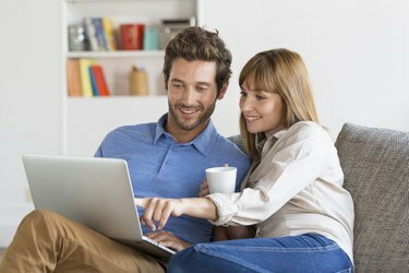Cuplu tânăr navigând pe internet cu laptop.