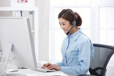 Dizüstü bilgisayarın önünde kulaklık takan genç iş kadını