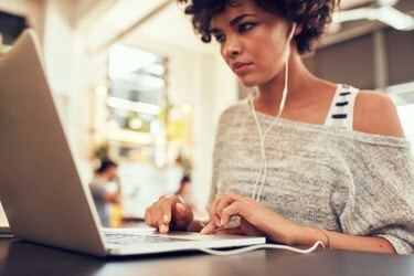 Donna che sembra impegnata a lavorare al computer portatile al bar