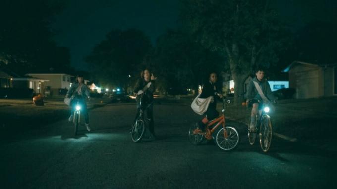 Les quatre stars de Paper Girls sont assises sur leurs vélos dans une rue sombre.
