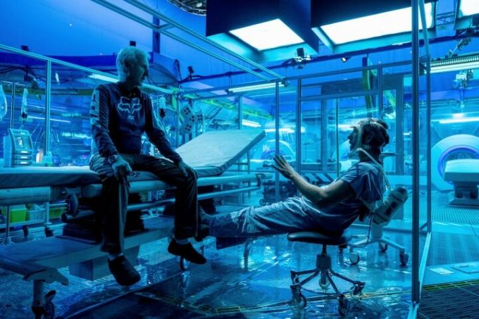 Jamesas Cameronas sėdi ant stalo ir diskutuoja apie kadrą su aktoriumi filmuojant Avataras: Vandens kelias.