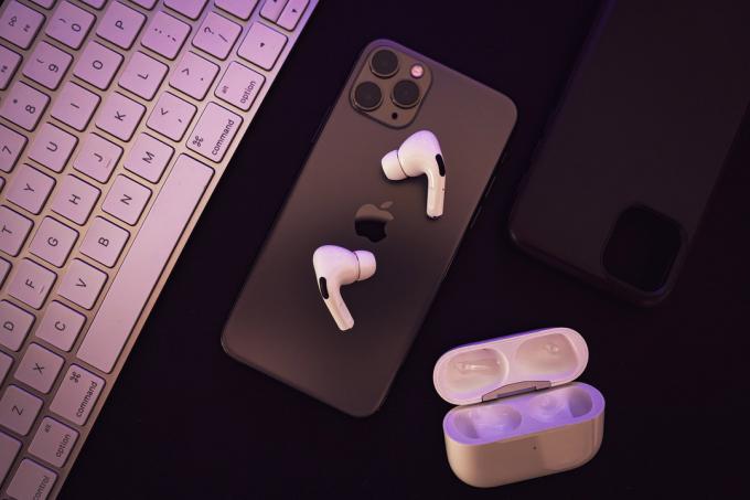 AirPods Pro დგას iPhone-ზე, ღია დამტენის ქეისით ახლოს.