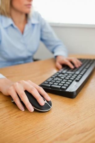 Blonde zakenvrouw met handen op muis en toetsenbord