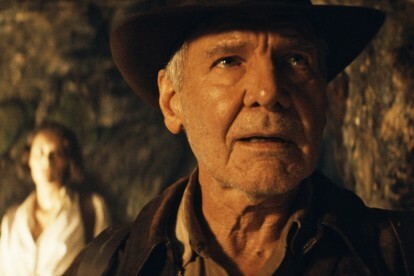 Indy, Indiana Jones and the Dial of Destiny'de bir mağarada bir şeye bakıyor.