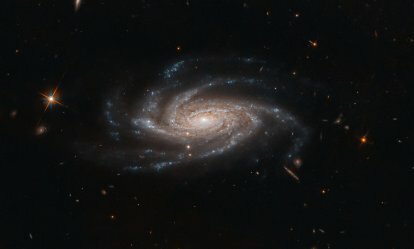 A galáxia espiral NGC 2008 está no centro do palco, com os seus braços espirais fantasmagóricos estendendo-se na nossa direcção, nesta imagem captada pelo Telescópio Espacial Hubble da NASAESA. 