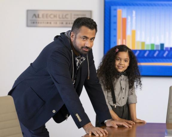 Kal Penn és Rupali Redd egy íróasztalra támaszkodnak a Mikulások egyik jelenetében.