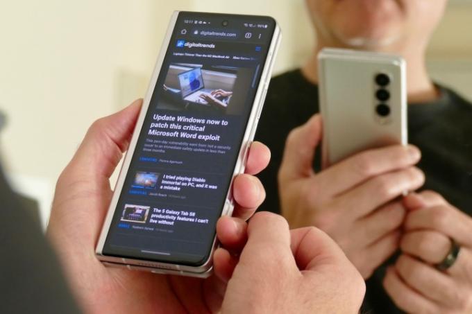 Mann som holder en Galaxy Z Fold 3 som viser et nettleservindu på den ytre skjermen.