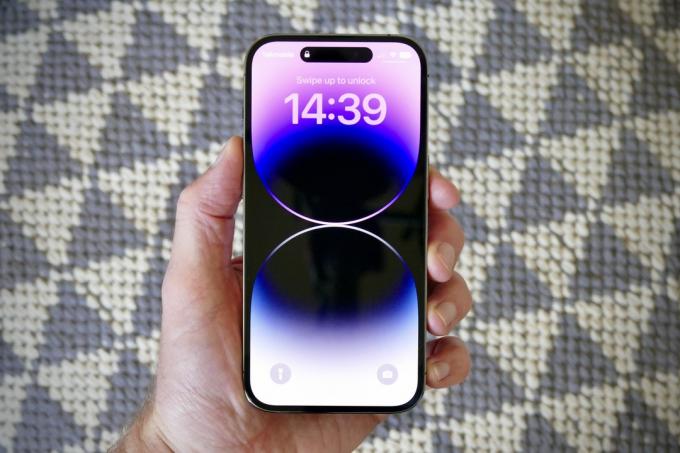 iPhone 14 Pro holdt i en manns hånd og viser skjermen.