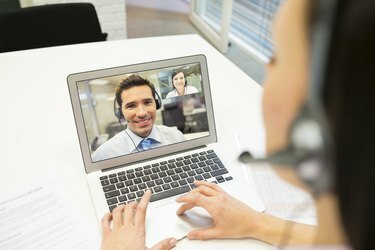 Pengusaha wanita di kantor pada konferensi video dengan headset, Skype