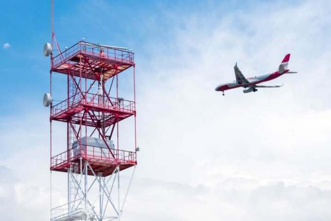 Passagiersvliegtuigen vliegen langs een grote radiocommunicatietoren.