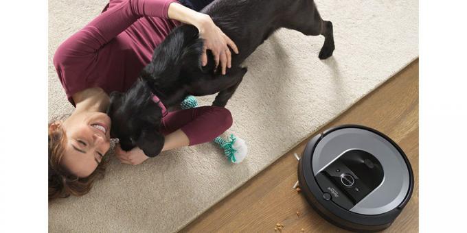 L'iRobot Roomba i8+ utilizzato in un soggiorno accanto a una donna e al suo cane.