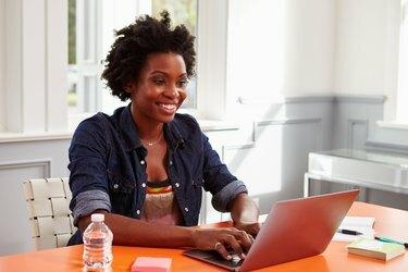 Jeune femme noire à l'aide d'un ordinateur portable à un bureau, gros plan