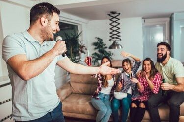Grup de prieteni jucând karaoke acasă