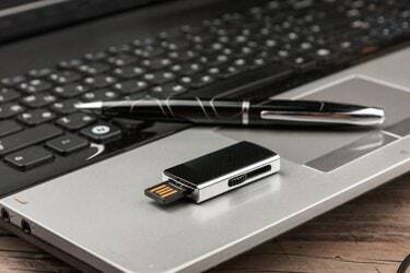 USB flash disk ležící na klávesnici notebooku a peru