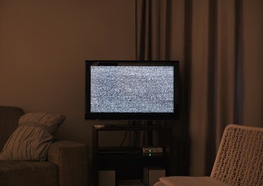Затемненная гостиная со статическим шумом на экране телевизора