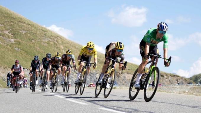 Ciclistas profissionais andando por uma estrada.