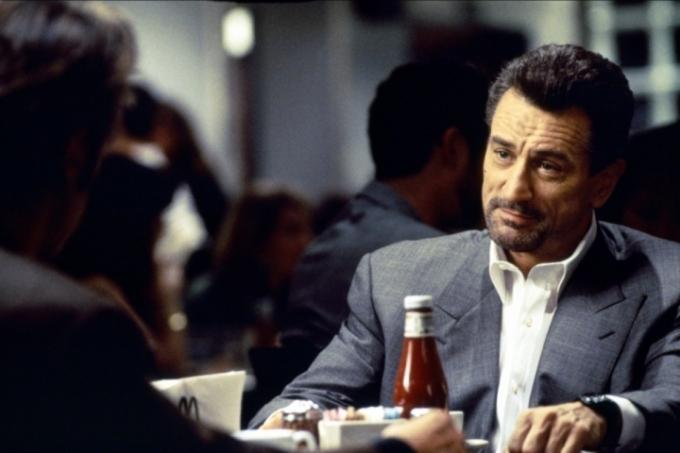 Robertas De Niro šypsosi žiūrėdamas į Alą Pacino Michaelo Manno filme „Heat“.