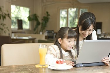 Mor og datter bruger bærbar computer på en cafe