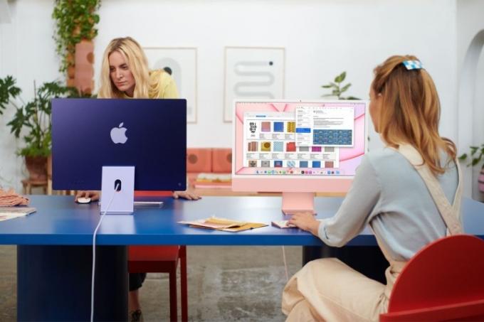 Zwei Personen nutzen iMacs auf einem Schreibtisch in einem Büro.