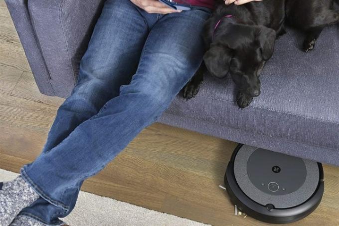 En iRobot Roomba-robot støvsuger under en sofa.