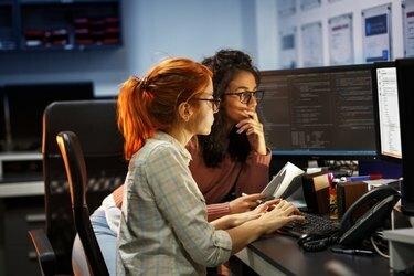 Δύο γυναίκες προγραμματιστές που εργάζονται σε νέο έργο. Δουλεύουν αργά το βράδυ στο γραφείο.