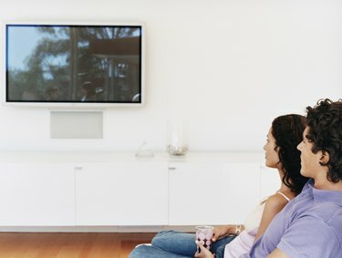 Cuplu care se uită la un televizor cu ecran plat în casa lor