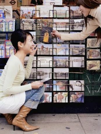 Twee jonge vrouwen bij souvenirstalletjes, ansichtkaarten uitkiezen