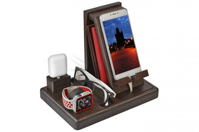 Zdjęcie przedstawia Apple iPhone, Apple Watch i parę okularów w stacji dokującej z litego drewna