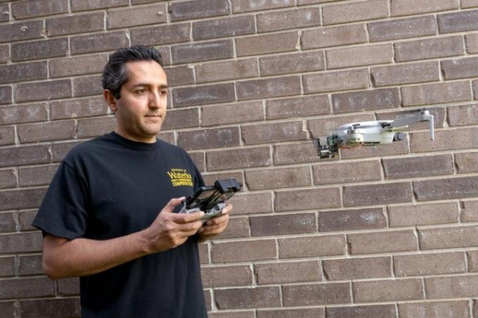 Profesor Ali Abedi z Wi-Peepom, ki stoji ob zidu.