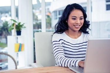 Sorridente donna asiatica che utilizza laptop