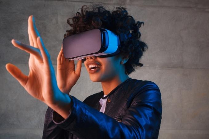 Una mujer extendiendo la mano mientras usa un visor de realidad virtual.