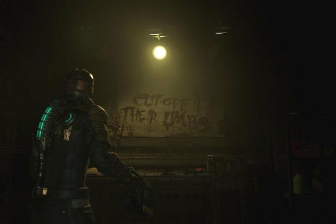 Uma captura de tela do remake de Dead Space que mostra Isaac olhando para uma escrita na parede que diz “Corte seus membros” com sangue.