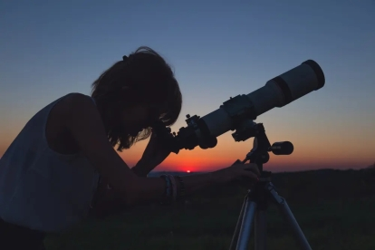 žena koja viri u teleskop