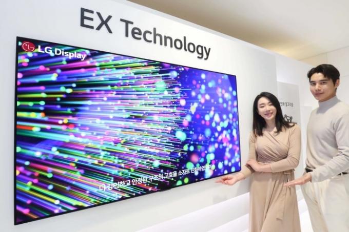 LG DisplayのOLED EXパネルのデモの横に立つモデルたち。