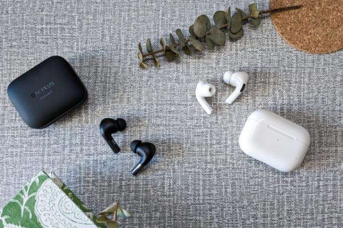 OnePlus Buds Pro 2 i svart och AirPods Pro första generationen i vitt på en vit och grå bordsskiva. 