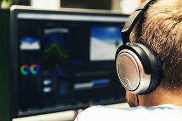 homme faisant du montage vidéo sur ordinateur avec un casque allumé