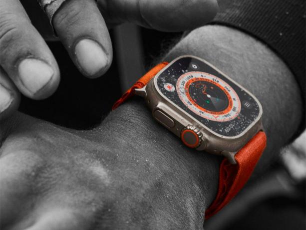 남자의 팔에 걸린 오렌지색 Apple Watch Ultra를 클로즈업하세요.