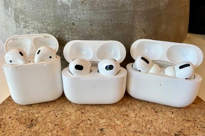 AirPods 3, AirPods und AirPods Pro sitzen in ihren Ladehüllen.